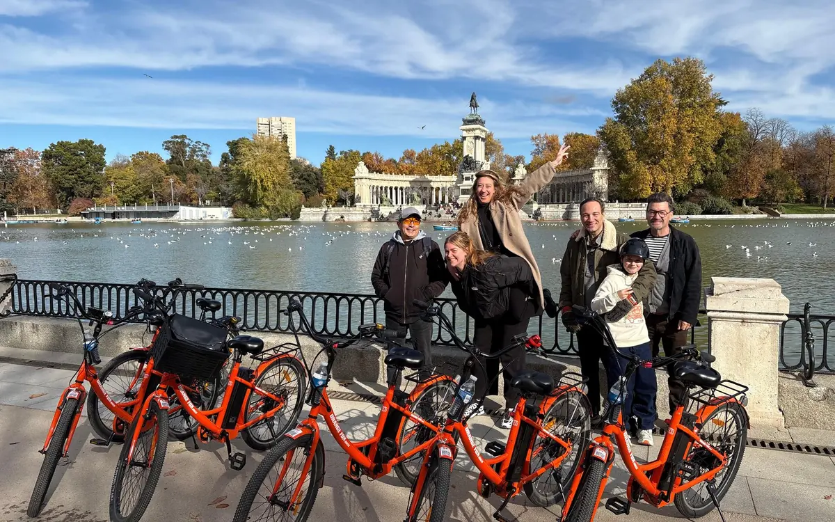 A guided group standing with their bikes beside the lake in Retiro Park, Madrid