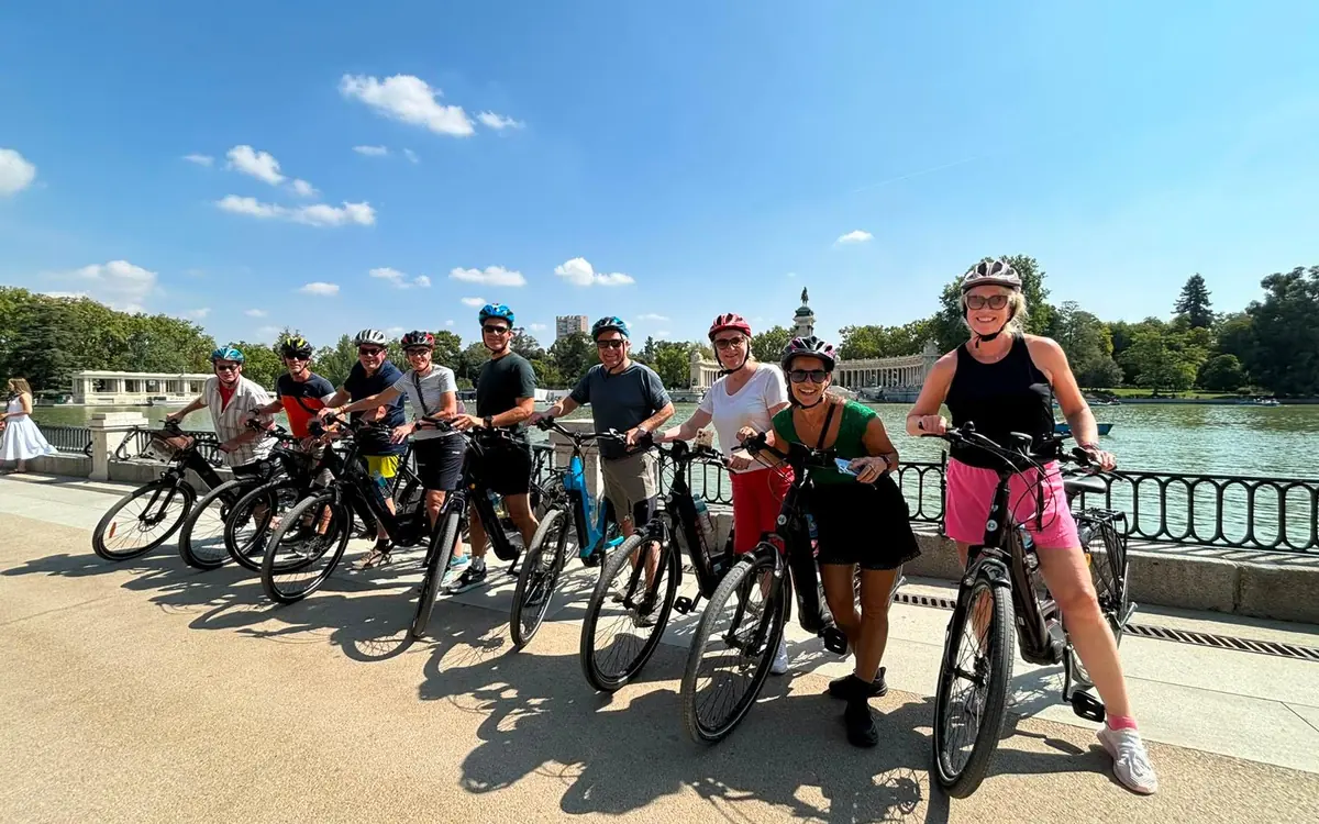 Riders resting on their bikes along the railing beside the lake in Retiro Park, Madrid