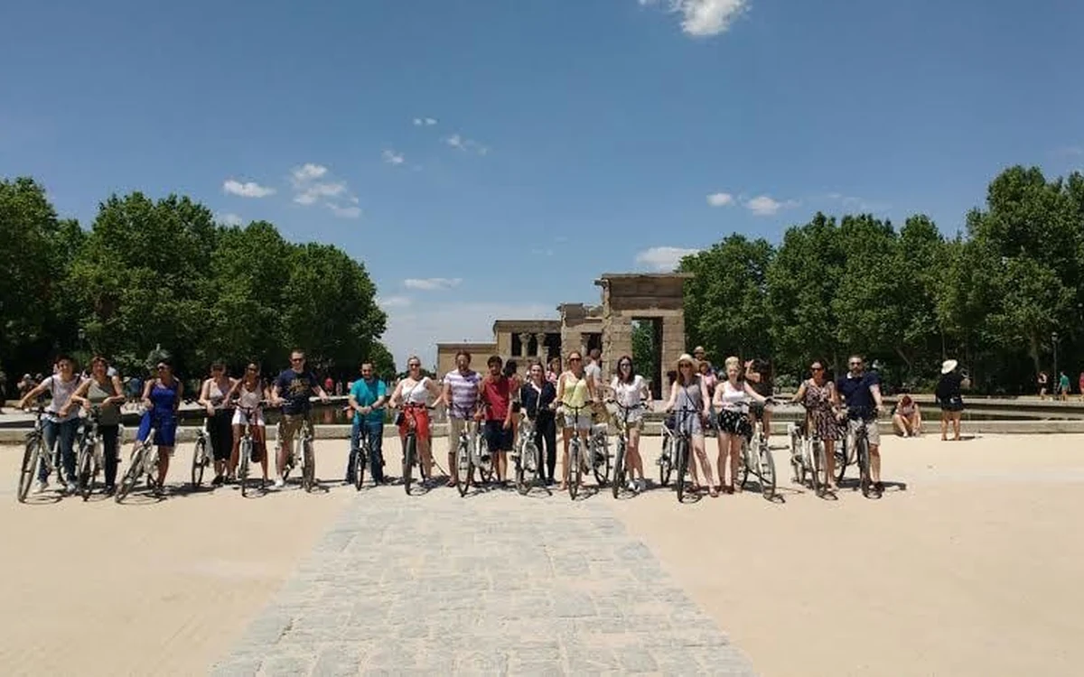 A large guided group halted with their electric bikes on a wide open esplanade in Madrid