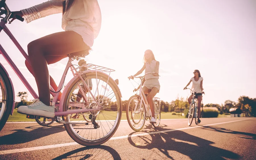 Two riders on a sunlit path, one of them pedalling into the low sun