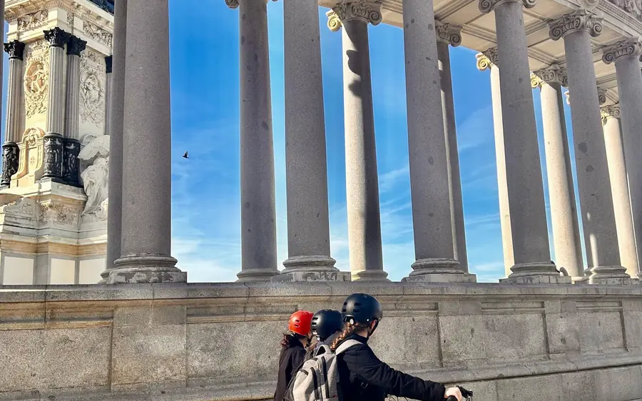 A rider passing below the tall colonnade of the monument by the lake in Retiro Park